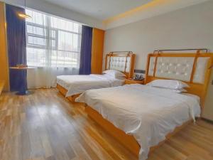 济阳银座佳驿精致酒店（济阳汽车总站店）的一间卧室设有两张床和大窗户