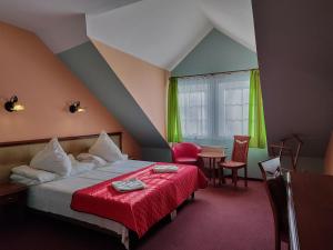 卡尔帕奇DW米喜客酒店的一间卧室配有一张带红色毯子和桌子的床。