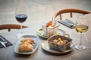 巴塞罗那Catalonia La Maquinista的一张桌子,上面放着两杯葡萄酒和一盘食物