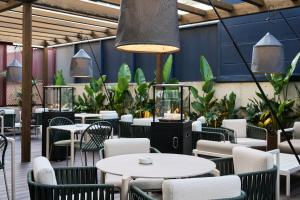 巴塞罗那Catalonia La Maquinista的一间设有白色桌椅的餐厅,种植了植物