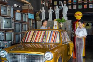普吉镇葵普住宿加早餐旅馆的两个女人站在商店里一辆黄色汽车旁边