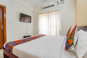 蒂鲁帕蒂FabHotel S V Homestay Tirupati的卧室配有一张带彩色枕头的大型白色床。