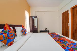 蒂鲁帕蒂FabHotel S V Homestay Tirupati的一间卧室配有带色彩缤纷枕头的床。