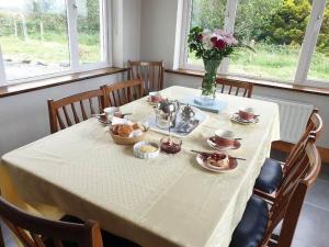 BallinaboyHillside House的一张桌子,上面有白色的桌布和花瓶