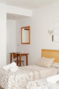 贝尼多姆Hotel Santa Faz的配有镜子和桌子的客房内的两张床