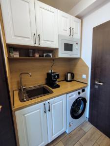 瓦尔纳Aпартамент 5的厨房配有白色橱柜、水槽和洗衣机。