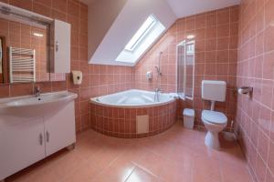 佩奇Szinbád Hotel的带浴缸、卫生间和盥洗盆的浴室