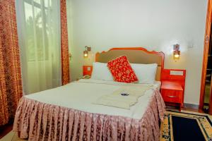 鲁亨盖里Home Inn Hotel Rwanda的一间卧室配有一张带红色枕头的大床