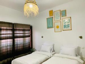 塔姆拉赫特乌兹达尔Darna Surf House Morocco的配有吊灯的客房内的两张床