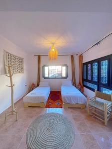 塔姆拉赫特乌兹达尔Darna Surf House Morocco的一间卧室配有两张床和吊灯。