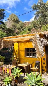 LoderoStudio Mazo La Habitación的黄色的房子前面设有桌椅