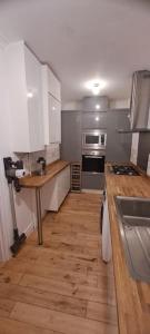 卡迪夫3 Bed Home in Heart of Cardiff的厨房铺有木地板,配有白色橱柜。