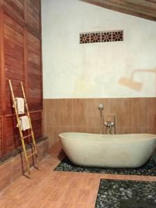 希德门Loka Amertha的带浴缸的浴室,设有木墙