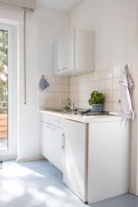 施瓦格明德Pension Krone的白色的厨房配有白色橱柜和水槽