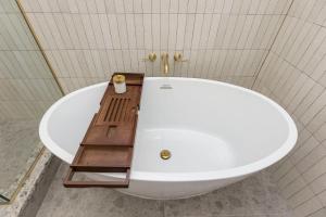 路易斯威尔Modern Mid Century Getaway. Luxury by Hollyhock的浴室设有白色浴缸,配有木桌