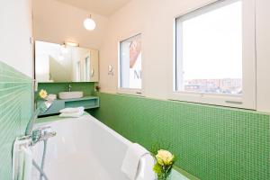维斯马新奥尔良酒店的绿色瓷砖浴室设有浴缸和水槽
