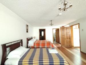 拉塔昆加Hotel Rosim Cotopaxi的一间卧室配有两张床和吊灯。