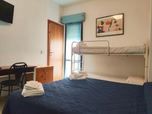 里米尼珍尼斯酒店的一间卧室配有一张双层床和一张书桌