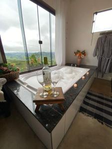 贡萨尔维斯Pousada Vitória的浴室设有浴缸,桌子上放有两杯酒杯
