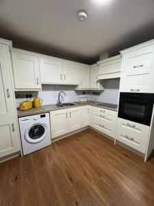 布莱克莱恩Blacklion prime location apartment的厨房配有白色橱柜、水槽和洗碗机。