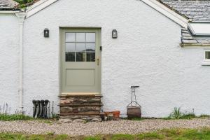 瓦特米尔洛克Mellguards, 4-Bed Country Cottage, in Howtown的白色的房子,有门和石柱