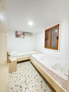 都拉斯Bellavista Villa的白色的客房设有两张床和窗户。