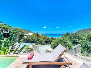 Anse Marcel Villa Romane private pool breathtaking sea view的游泳池旁阳台的白色躺椅