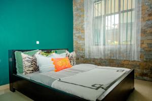NyakinamaIbuye Villa的窗户客房内的一张带色彩缤纷枕头的床
