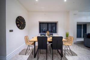 FarnleyModern 2-Bed Townhouse, Conveniently Located Near Leeds City Centre - Perfect for Corporate Stays的餐桌、椅子和墙上的时钟