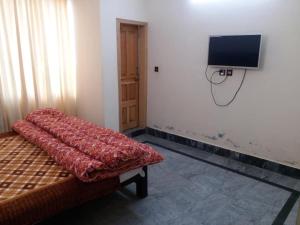 穆扎法拉巴德Kashmir Inn Hotel的一间配有沙发的房间和墙上的电视