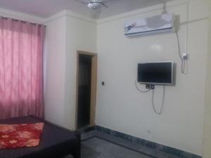 穆扎法拉巴德Kashmir Inn Hotel的一间设有床铺和墙上电视的客房