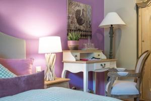 巴特奥塞瓦尔德鲁贝特住宿加早餐旅馆的一间卧室设有紫色墙壁和一张带台灯的桌子
