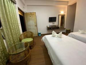 大吉岭Lamahatta Residency的酒店客房带两张床和一张桌子以及椅子。