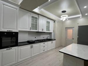奥什Квартира на Мурас Ордо的厨房配有白色橱柜和黑色家电