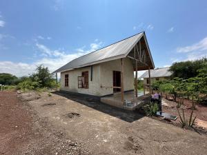 姆托瓦姆布Manyara Exclusive Safari Lodge的田野上带金属屋顶的小房子