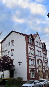 卡塞尔Wohnung in Kirchditmold的一座白色和红色的建筑,前面有汽车停放