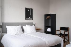 哥本哈根Beach Trail apartments by Daniel&Jacob's的一间卧室配有一张带白色床单的大床和椅子