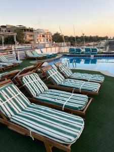 开罗Queen Isis floating hotel的一组躺椅,坐在游泳池旁