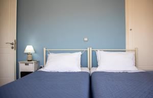 爱琴娜岛The Garden House的卧室内的两张床,配有蓝色的墙壁和白色的枕头