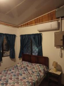 拉克鲁斯Casa de campo en la playa的一间卧室配有一张带蓝色窗帘的床和一扇窗户