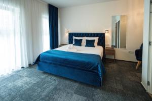 奥拉迪亚ALIVE HOTEL的一间卧室配有一张带蓝色毯子的大床