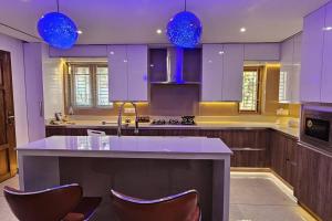 坎努尔Thekkumbath Sea breeze的厨房配有紫色橱柜和带椅子的柜台。