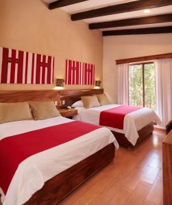 圣克里斯托瓦尔-德拉斯卡萨斯德尔山谷酒店大厦的一间卧室配有两张红色和白色床单