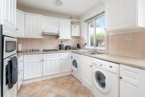 吉尔福德Prime Living的厨房配有白色橱柜、洗衣机和烘干机