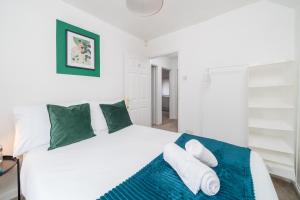 吉尔福德Prime Living的卧室配有带绿色枕头的大型白色床