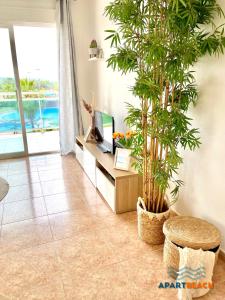 拉皮内达APARTBEACH LOS JUNCOS 2 RESIDENCIAL y JUNTO PLAYA的一间带电视和植物的客厅