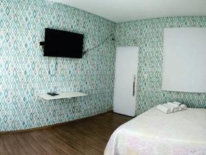 奥林匹亚OLÍMPIA APARTS Kitnet com cozinha e banheiro privativo PISCINA AQUECIDA的一间卧室配有一张床,墙上配有电视