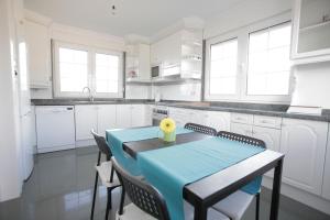希洪Gijon Surf Hostel的白色的厨房配有蓝色的桌子和椅子