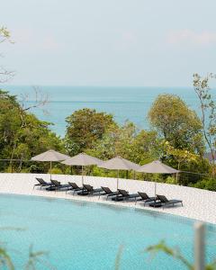 停泊岛Perhentian Marriott Resort & Spa的游泳池旁的一排椅子和遮阳伞