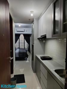 巴淡岛中心Comodo Apartemen Pollux Habibie Rooftop-SeaView的厨房配有白色橱柜和一张位于底部的床。